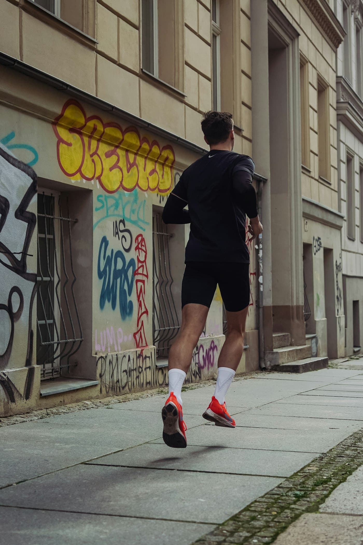 A runner in black training kit on a city street